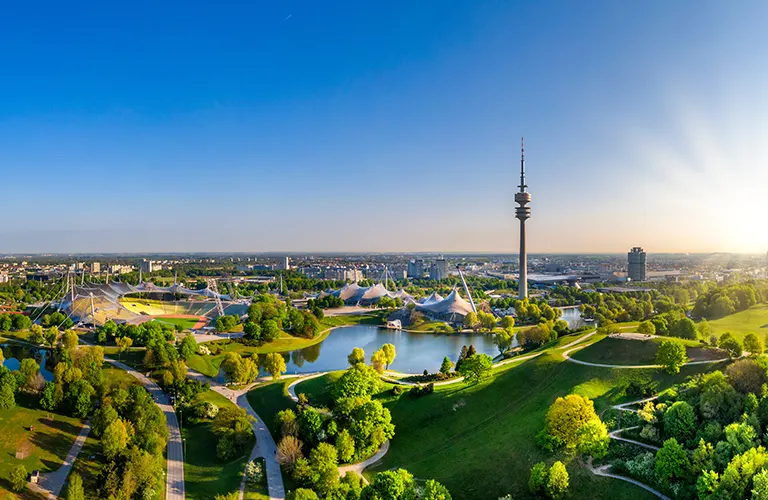 IP-Seminar München, BOEHMERT & BOEHMERT Foto des grünen Münchens aus der Luft, mit Blick auf dem Olympiaturm, das Olympiastadium und den sommerlichen Olympiapark.